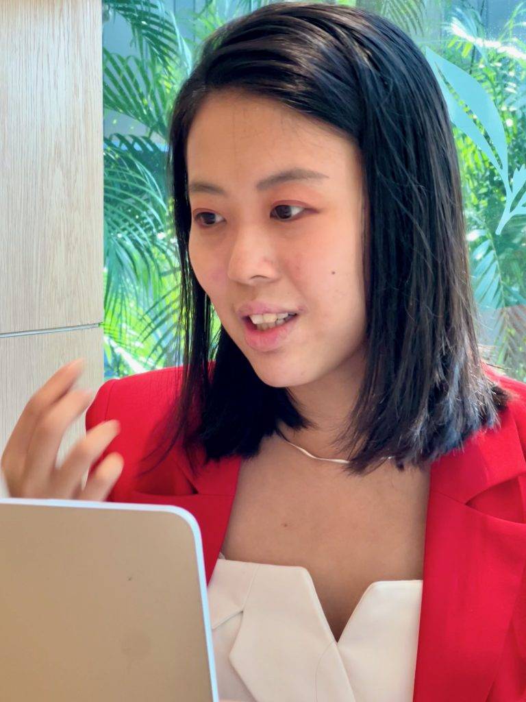 Woman in red blazer using a laptop.