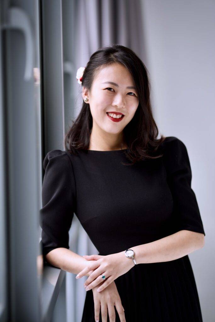 Smiling woman in black dress by window